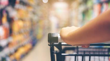 close up of arm pushing cart in isle of grocery store